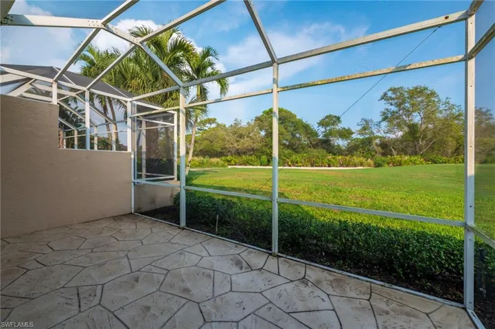 Screened enclosure with a textured concrete patio, offering expansive green space beyond