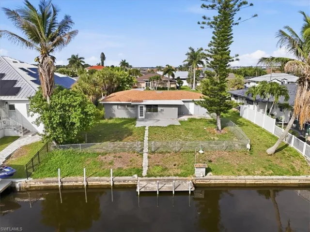 Waterfront property featuring a tile roof, stucco exterior, rear patio, and a private dock with pilings