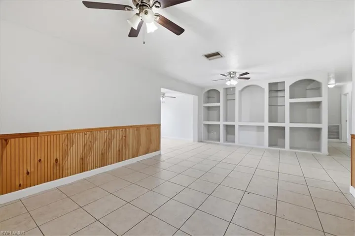 Spacious interior featuring built-in shelving, ceiling fans, wainscoting, and tile flooring