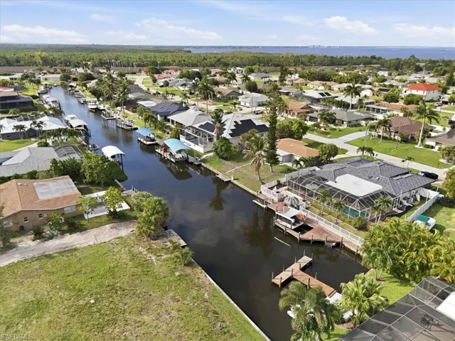 Canal-front property featuring a screened-in pool enclosure, private dock, and mature palm trees