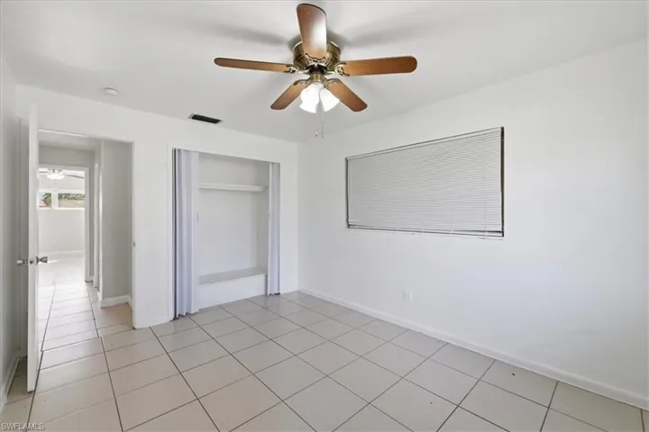 Room featuring a ceiling fan with wood-finish blades and integrated lighting, square ceramic tile flooring, and a window with horizontal blinds