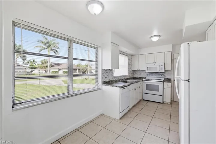 Kitchen featuring white cabinetry, a mosaic tile backsplash, and light-toned tile flooring