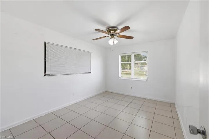 Interior room featuring ceramic tile flooring, white walls, and a ceiling fan with light fixture