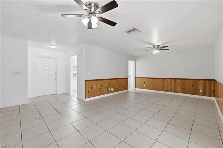 Spacious room featuring tile flooring, white walls, and beadboard paneling