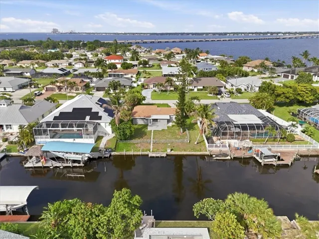 Waterfront property with direct canal access, featuring an enclosed pool deck and a boat dock with a covered lift