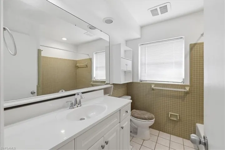 Bathroom featuring a white vanity with integrated sink, chrome faucet, and expansive wall-mounted mirror