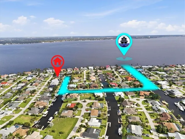 Aerial perspective of a waterfront residential community featuring canals, numerous homes with private docks, and direct access to a large body of water