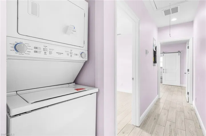 Washroom featuring attic access, stacked washer and clothes dryer, light wood-style flooring, and recessed lighting