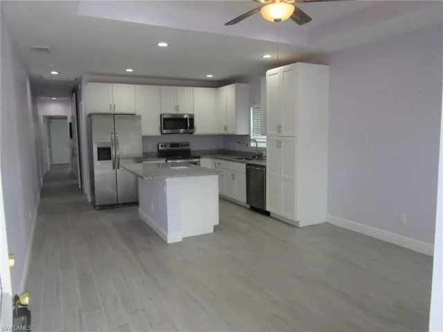 Kitchen featuring appliances with stainless steel finishes, ceiling fan, light wood-type flooring, white cabinetry, and a center island