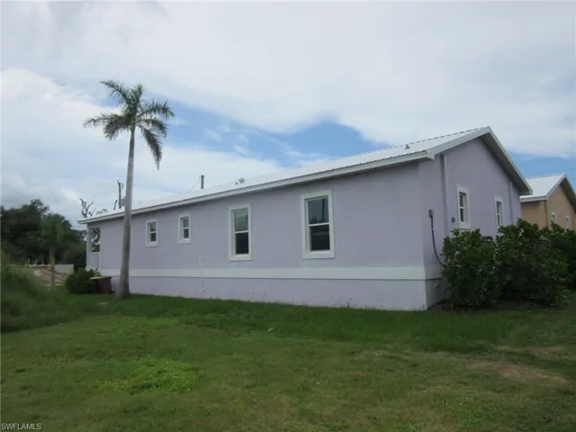 Back of house featuring stucco siding, a yard, and a metal roof