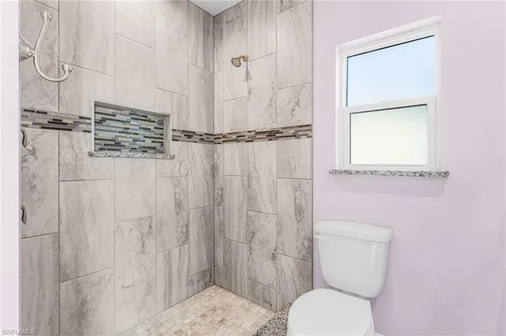 Bathroom featuring a tile shower and toilet