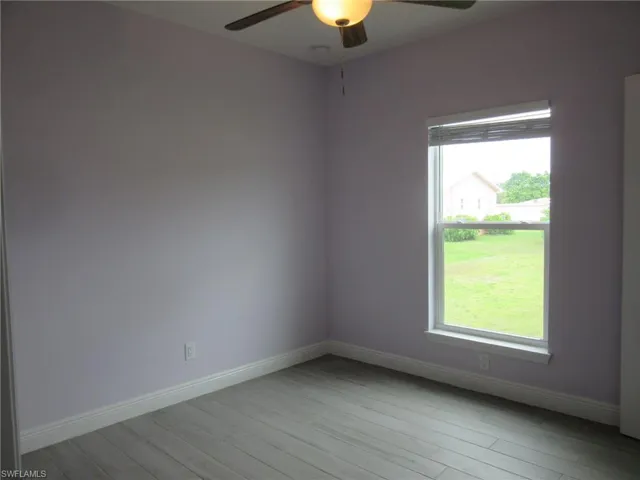 Unfurnished room with ceiling fan, healthy amount of natural light, and light wood-style flooring