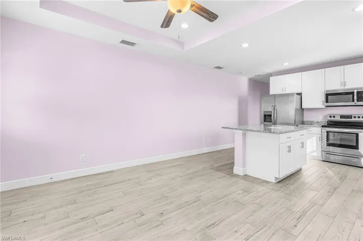 Kitchen featuring appliances with stainless steel finishes, recessed lighting, a kitchen island, ceiling fan, and white cabinetry