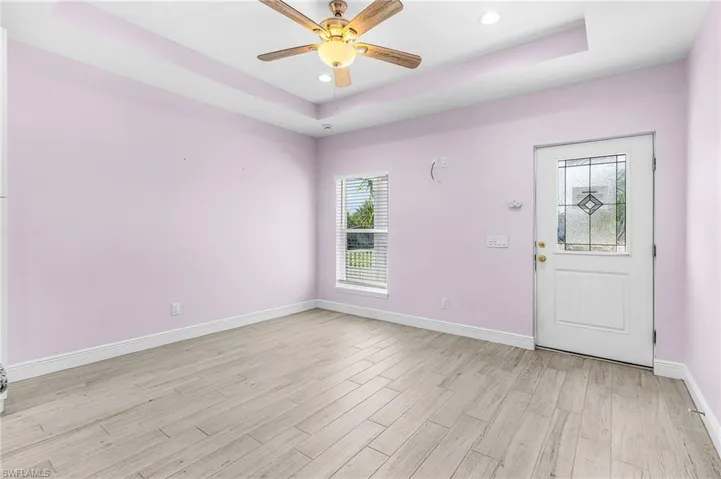 Entryway featuring a raised ceiling, light wood-style floors, ceiling fan, and recessed lighting