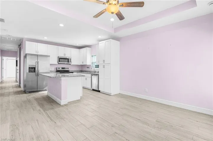 Kitchen with appliances with stainless steel finishes, a ceiling fan, a center island, light wood-style floors, and recessed lighting