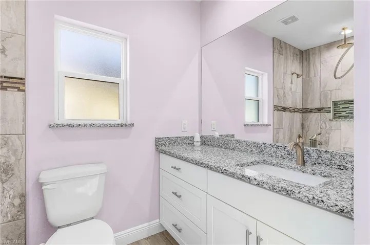 Full bath featuring vanity, a tile shower, and wood finished floors