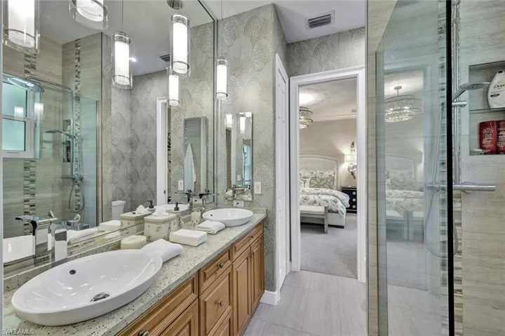 Beautiful guest bath  custom mirror, quartz countertop, custom cabinetry, frames glass walk in shower with niches and designer lighting