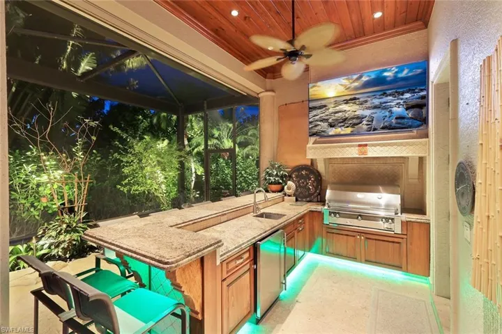 Large outdoor kitchen with glass grill, sizzler, hood, seats 8 plus guests and wood lined ceiling. Large built in TV all wired to the family room.