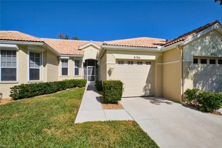 Mediterranean / spanish-style home featuring stucco siding, a front yard, driveway, an attached garage, and a tiled roof