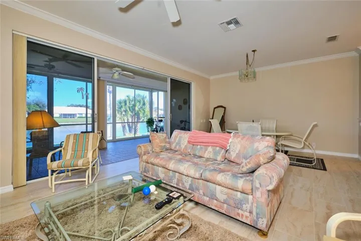 Living area with crown molding, ceiling fan, and a water view
