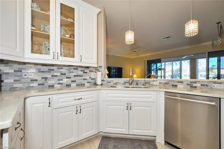 Kitchen with white cabinetry, pendant lighting, dishwasher, a ceiling fan, and ornamental molding