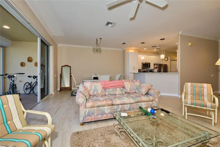 Living room with light wood-style floors, recessed lighting, ornamental molding, and ceiling fan