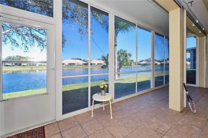Sunroom featuring plenty of natural light, tile patterned flooring, expansive windows, and a water view
