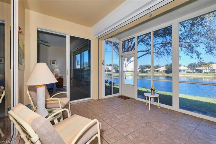 Sunroom featuring a water view, tile patterned flooring, and a residential view