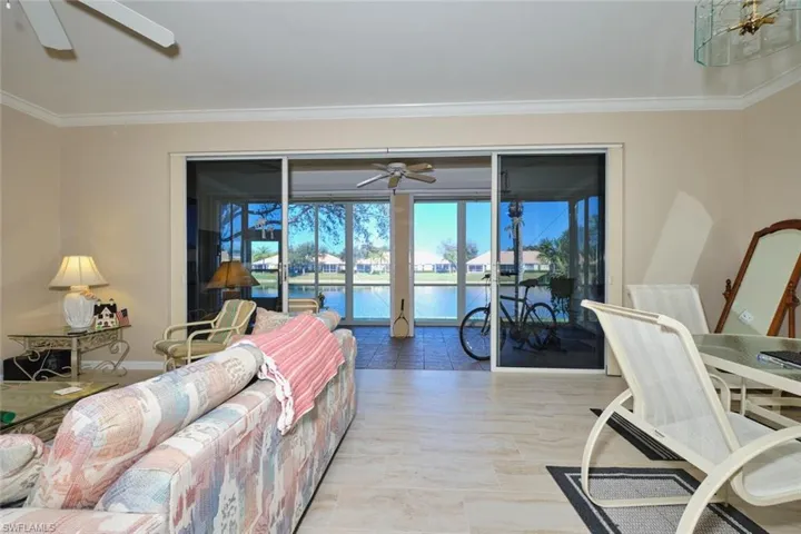 Living room with a ceiling fan, a water view, and crown molding