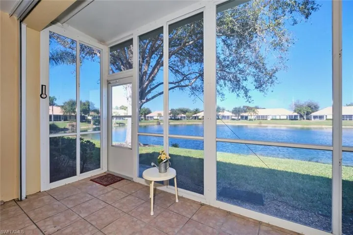 Unfurnished sunroom with a residential view, a water view, tile patterned floors, and floor to ceiling windows