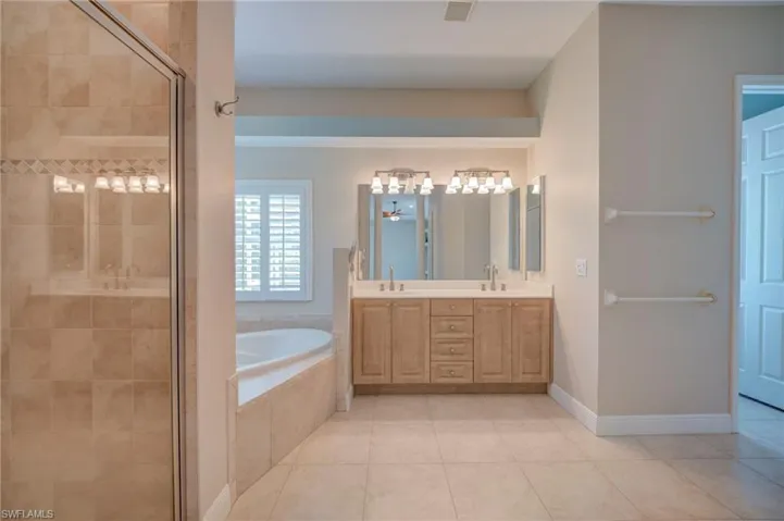 Bathroom with double vanity, a bath, light tile patterned flooring, and a stall shower