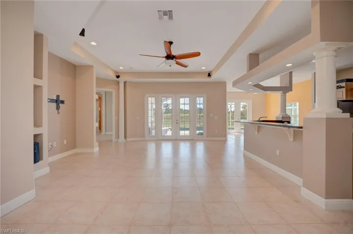 Unfurnished living room with french doors, ceiling fan, decorative columns, recessed lighting, and light tile patterned flooring