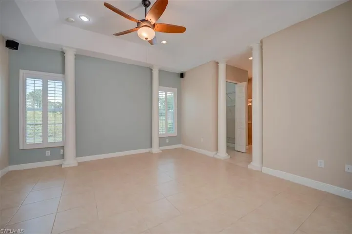 Unfurnished room with ornate columns, a ceiling fan, recessed lighting, a raised ceiling, and light tile patterned floors