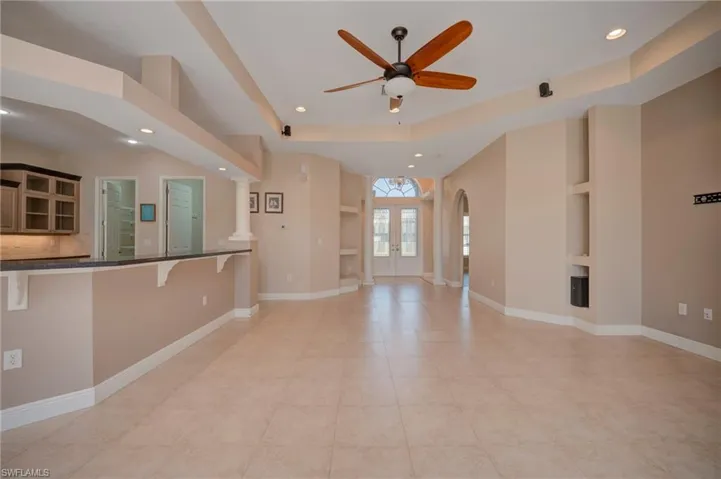 Unfurnished living room with recessed lighting, french doors, a raised ceiling, a ceiling fan, and arched walkways