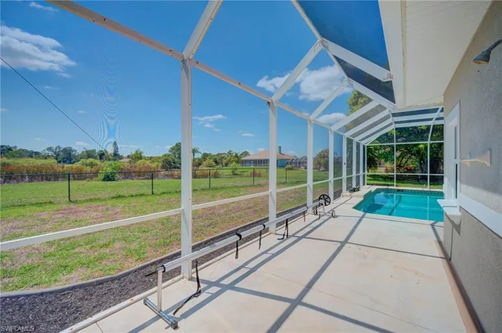 View of pool featuring a sunroom, patio surround, glass enclosure, and a fenced backyard