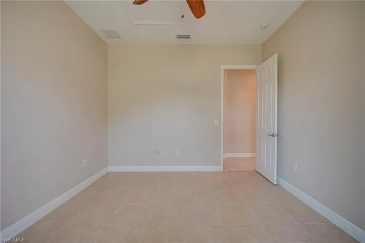 Empty room with a ceiling fan and light tile patterned flooring