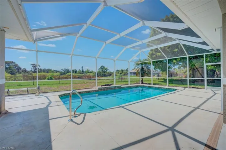 Outdoor pool with a lawn, a patio, a sunroom, and a lanai