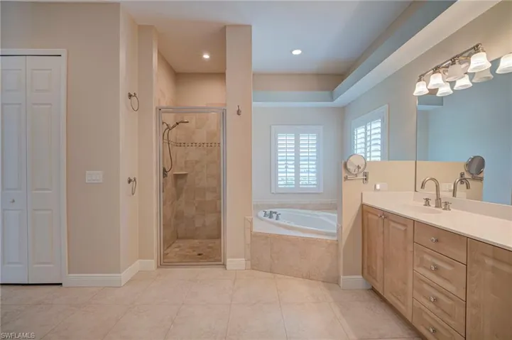 Bathroom with vanity, a bath, a shower stall, and a closet