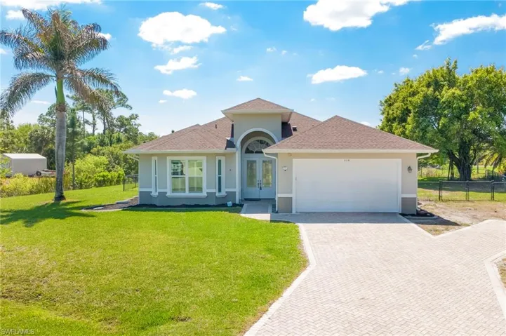 Modern home featuring an attached garage, decorative driveway, stucco siding, french doors, and roof with shingles