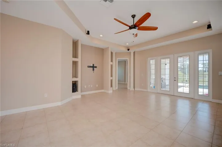 Empty room with a ceiling fan, a raised ceiling, recessed lighting, and french doors