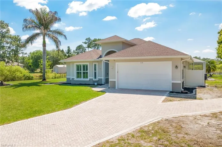 View of front of property with an attached garage, decorative driveway, stucco siding, a front yard, and a shingled roof