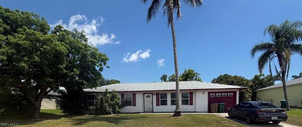 Single-story residence featuring a white exterior with red trim accents and a white metal roof