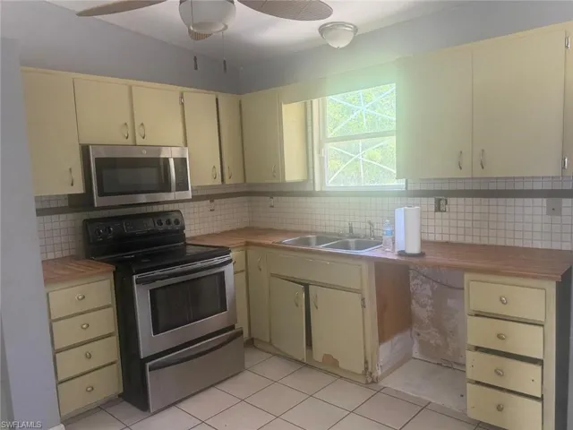 Kitchen featuring light-toned cabinetry, wood-finish countertops, stainless steel appliances, and a tiled backsplash