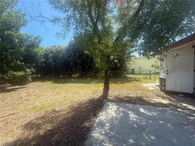 Expansive backyard featuring a mature tree, concrete patio, and perimeter fencing