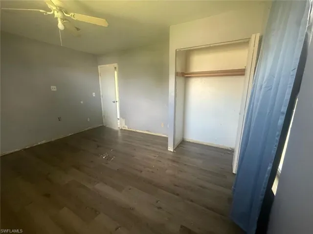 Room featuring wood-finish flooring, a ceiling fan, and a built-in closet with shelving and a hanging rod