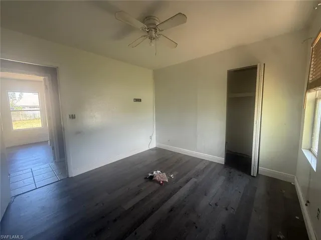 Room featuring wood-finish flooring, a ceiling fan with light fixture, and a window with blinds