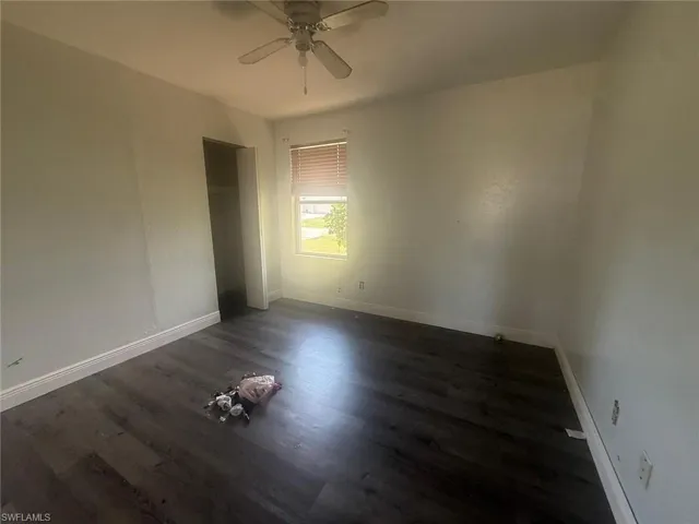 Room featuring wood-finish flooring, light-colored walls, and a ceiling fan