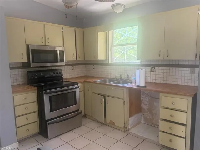 Kitchen featuring wood-finish countertops, stainless steel appliances, upper and lower cabinetry, and tiled flooring