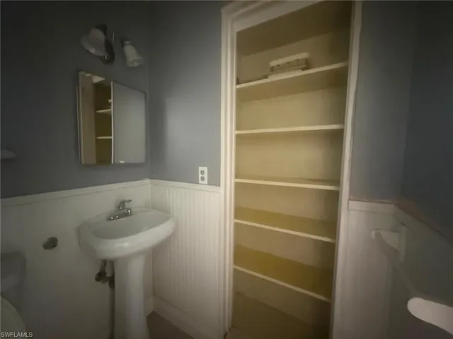 Pedestal sink with chrome faucet, medicine cabinet, and wall-mounted vanity lighting