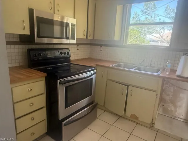 Kitchen featuring a stainless steel microwave and oven, a double basin sink, and a window above the sink